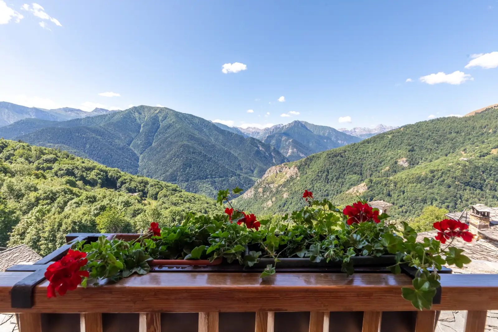 Gerani rossi sul balcone dell'agriturismo con le montagne della Valle Maira