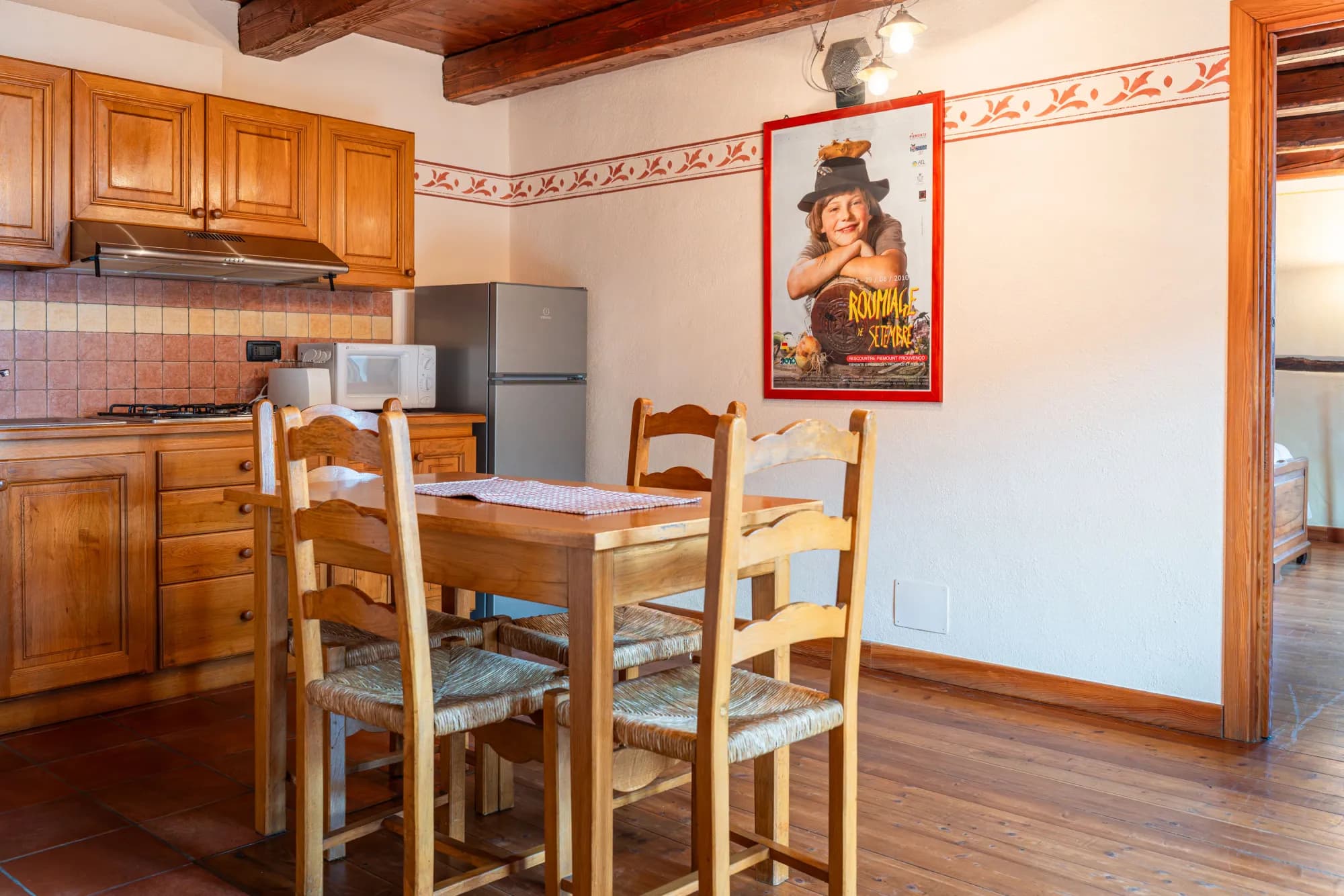 Appartamento Isabella: la cucina in legno e il tavolo da pranzo sotto le travi