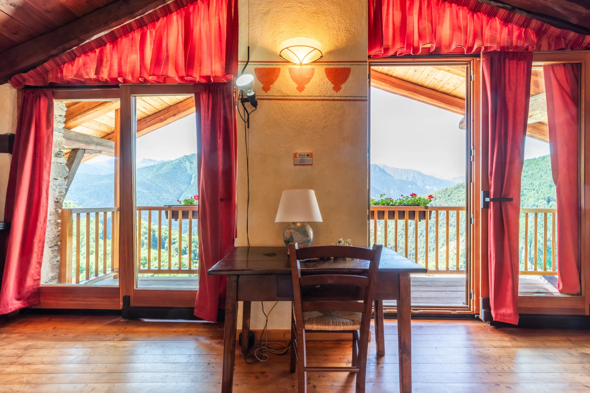 Appartamento Panorama: tavolo in legno tra le due porte-finestra aperte sui monti della Valle Maira