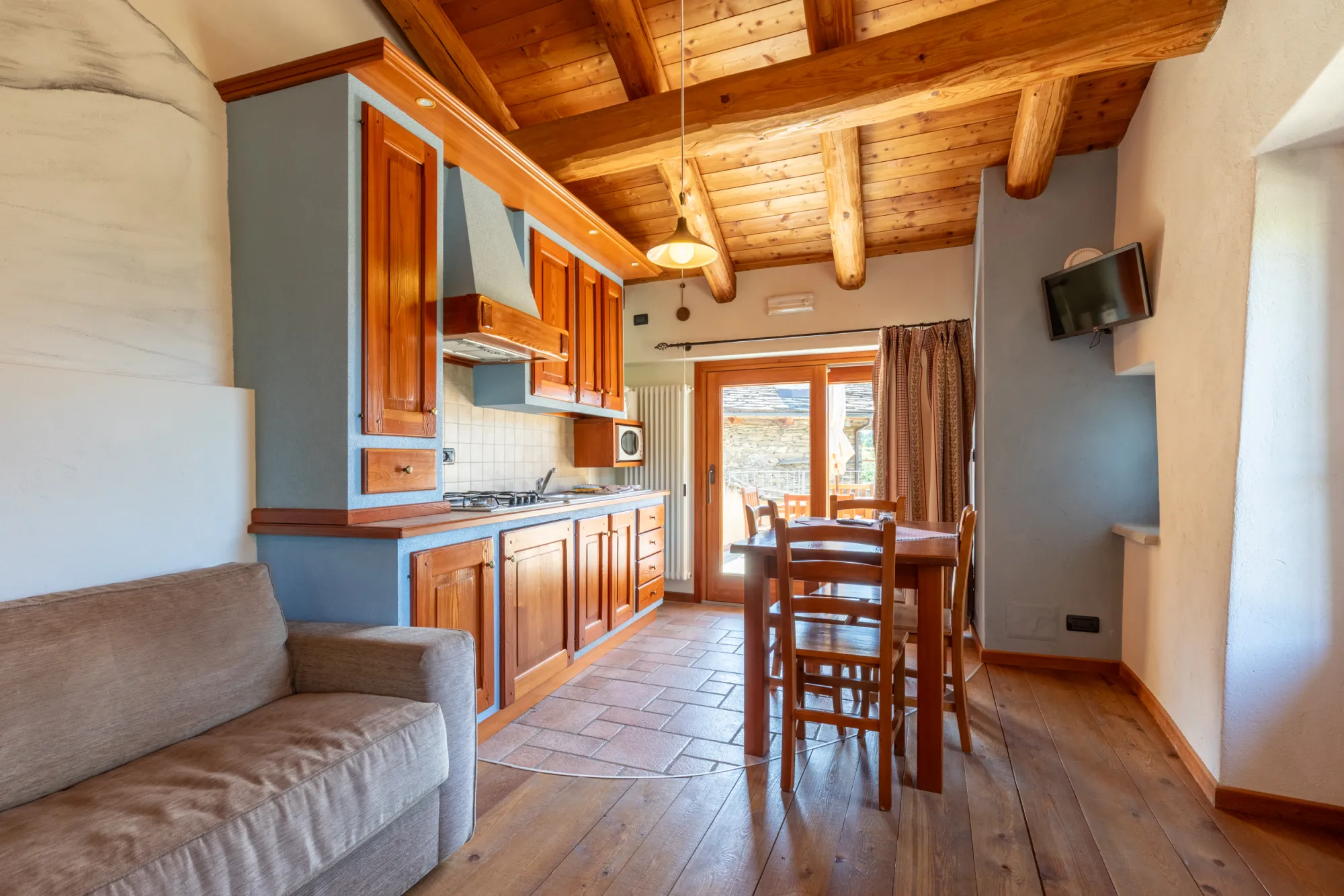 Appartamento Regina delle Alpi: la cucina-living con il divano sotto il soffitto in larice
